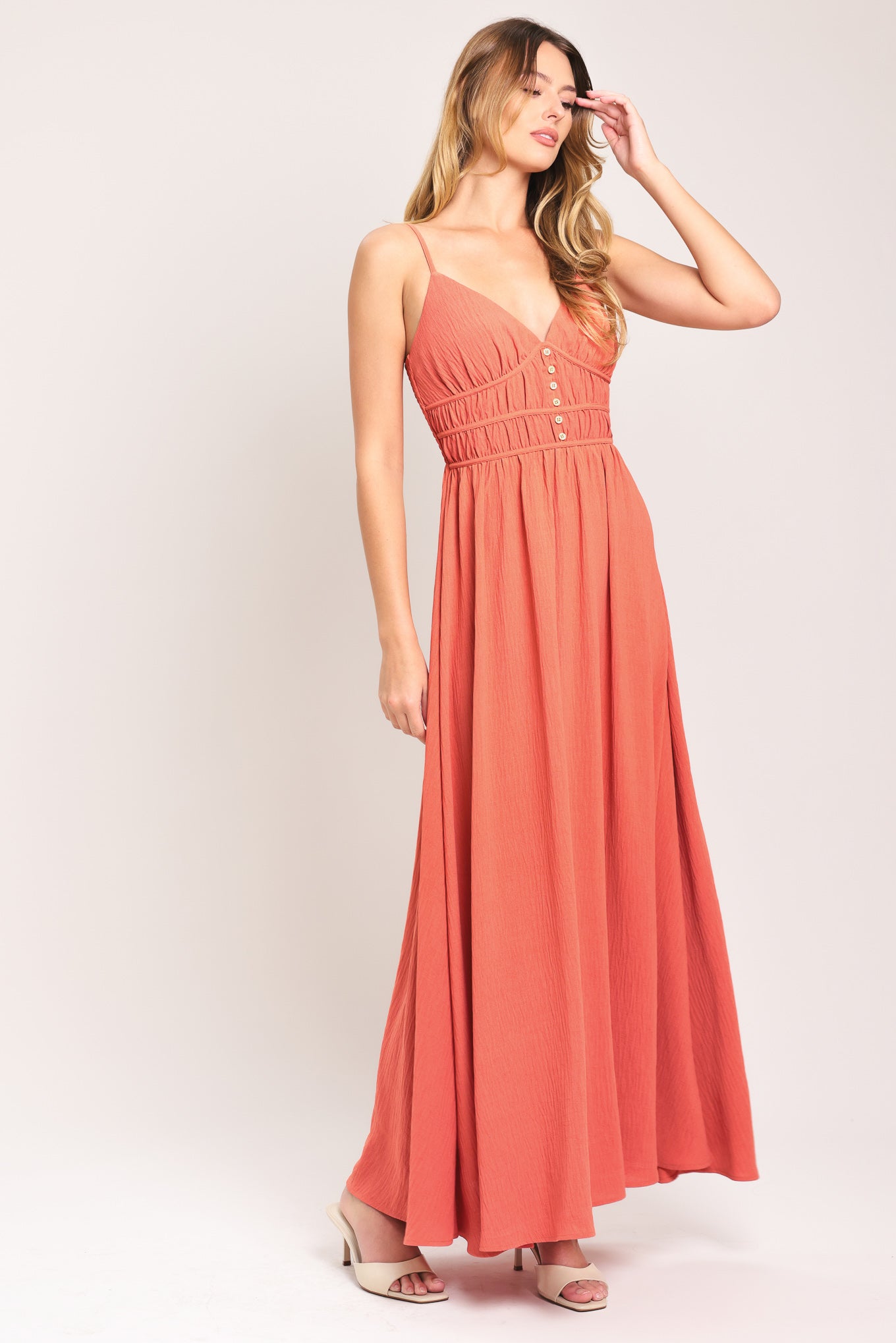 Woman wearing a coral maxi dress featuring cami top, waist yoke with shirring and button, elastic waist and smocked back bodice | Flying Tomato