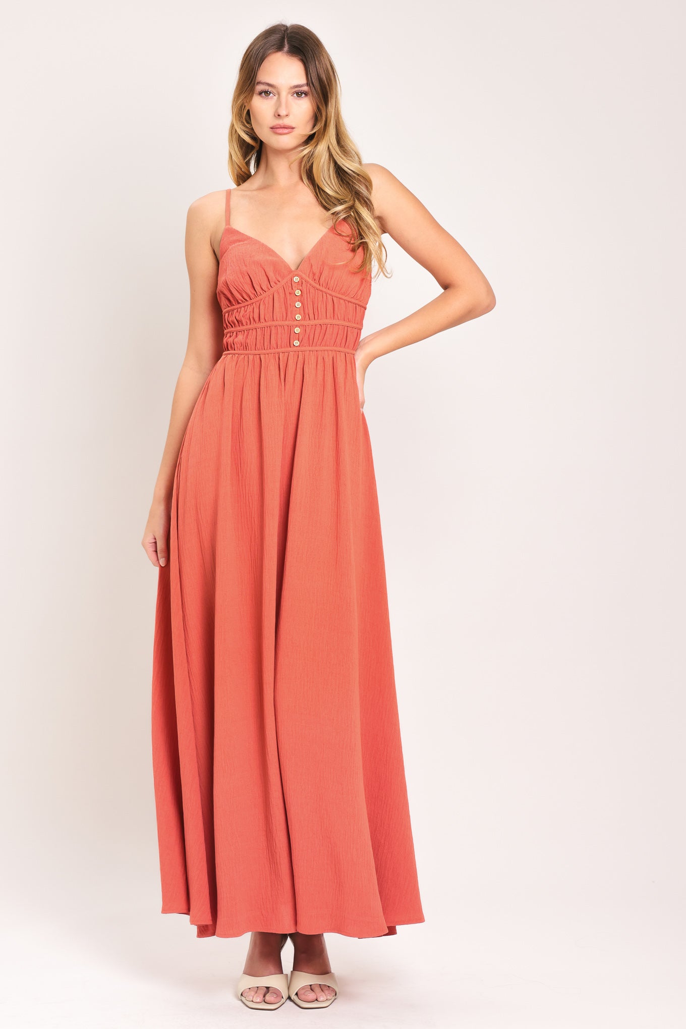 Woman wearing a coral maxi dress featuring cami top, waist yoke with shirring and button, elastic waist and smocked back bodice | Flying Tomato