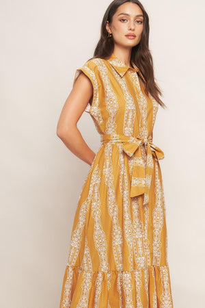 A printed woven midi dress featuring collar, button down, short sleeve, self sash tie and ruffled hemline