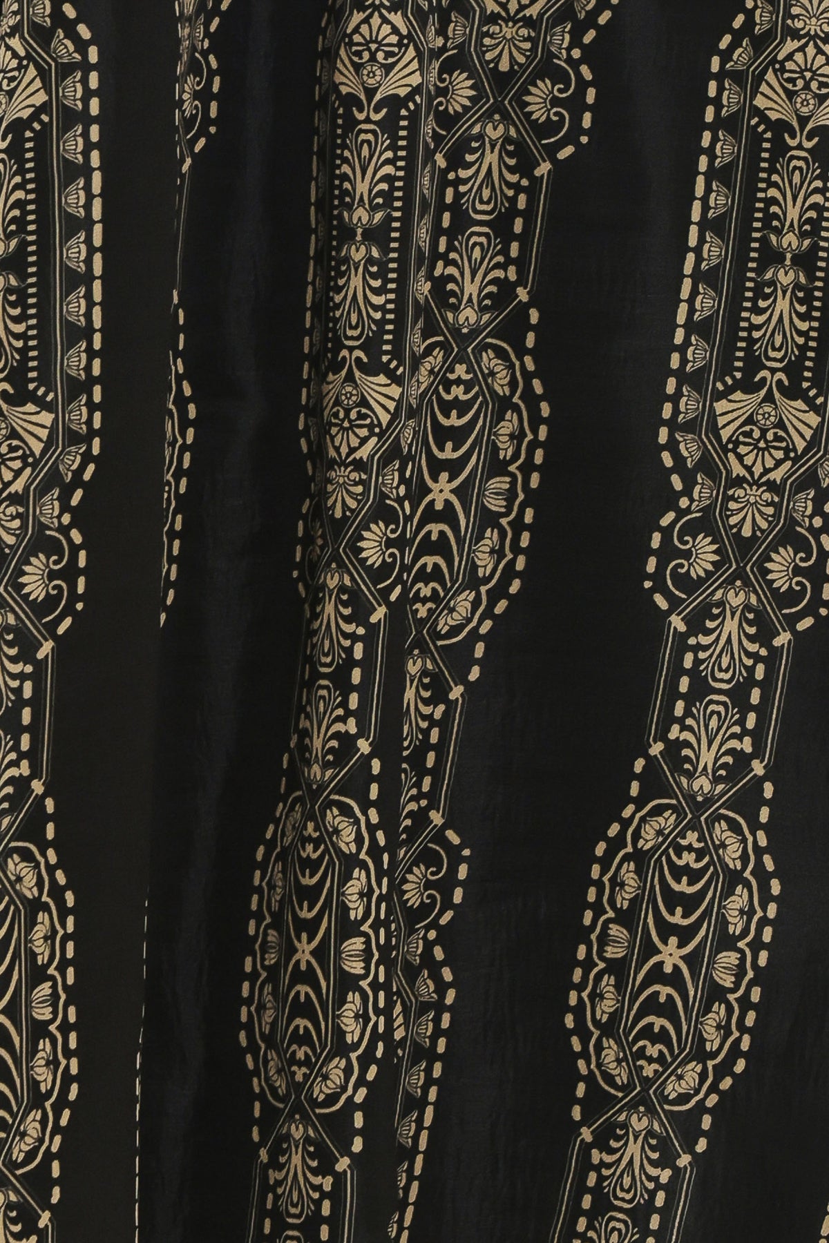 A close-up of a black fabric featuring vertical gold and beige ornate floral and geometric patterns.
