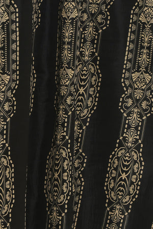 A close-up of a black fabric featuring vertical gold and beige ornate floral and geometric patterns.