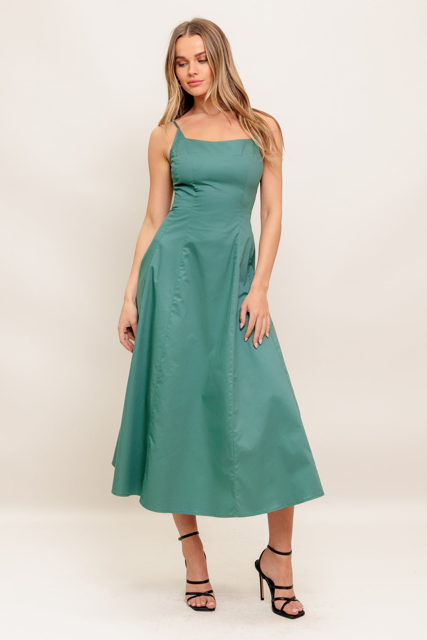 A solid woven midi dress featuring curved neckline, sleeveless, straps, circle skirt and back zipper closure