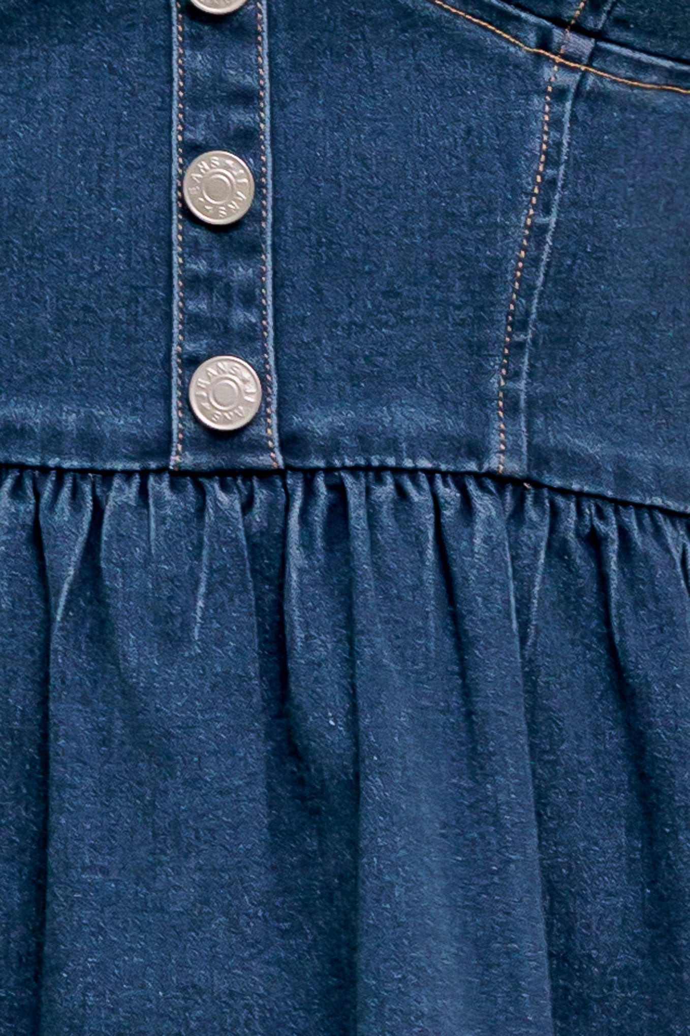 A washed denim mini dress featuring bustier top, straps, button down, ruffled hemline and back zipper closure.