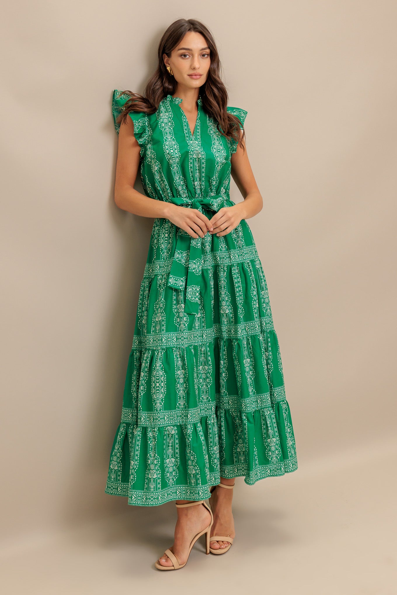 A printed woven midi dress featuring ruffled neckline with V center, short ruffle sleeve, elasticized waist with self sash tie and tiered skirt