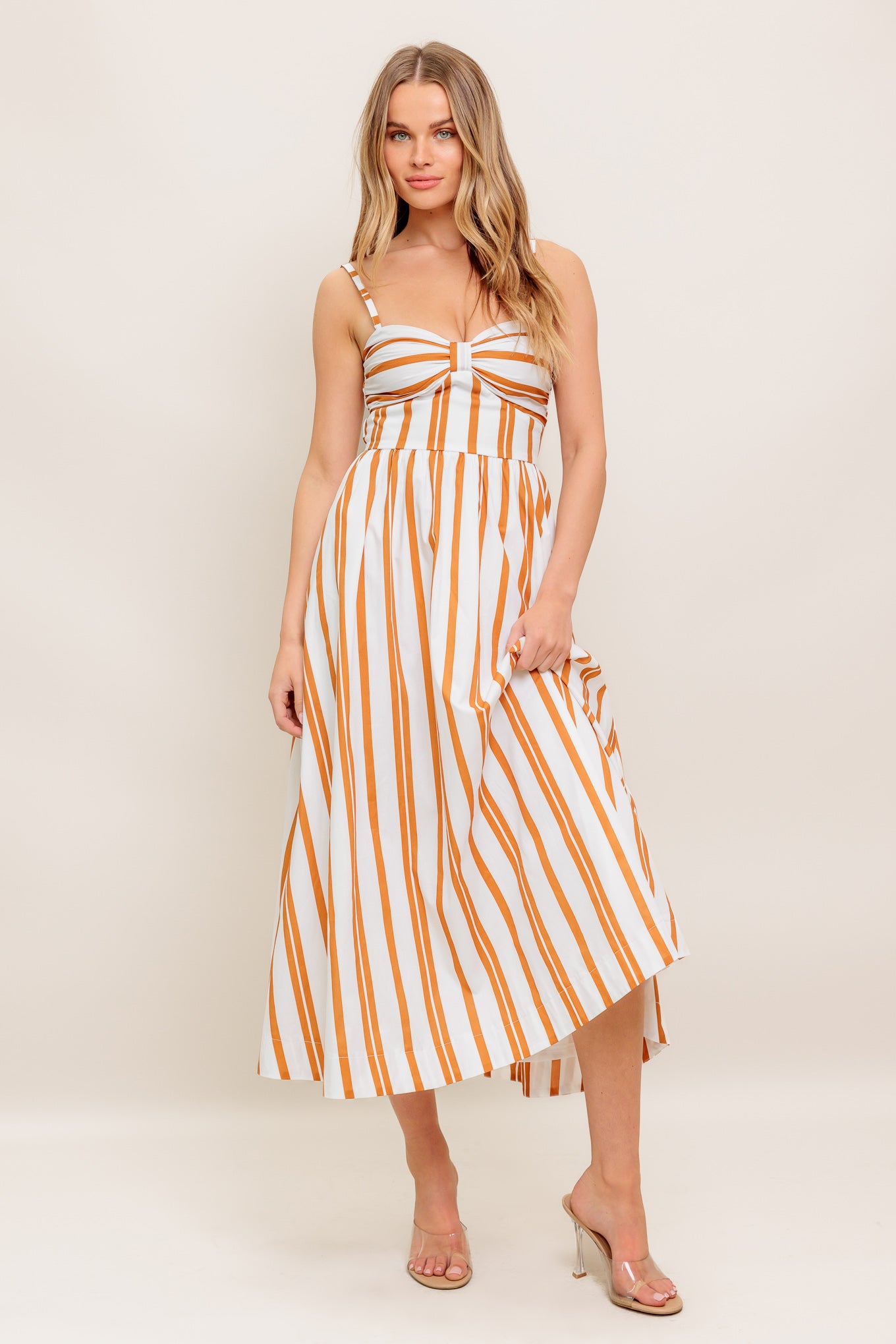 A striped woven midi dress featuring sweetheart neckline with shirred cup, straps, full skirt and smocked back bodice