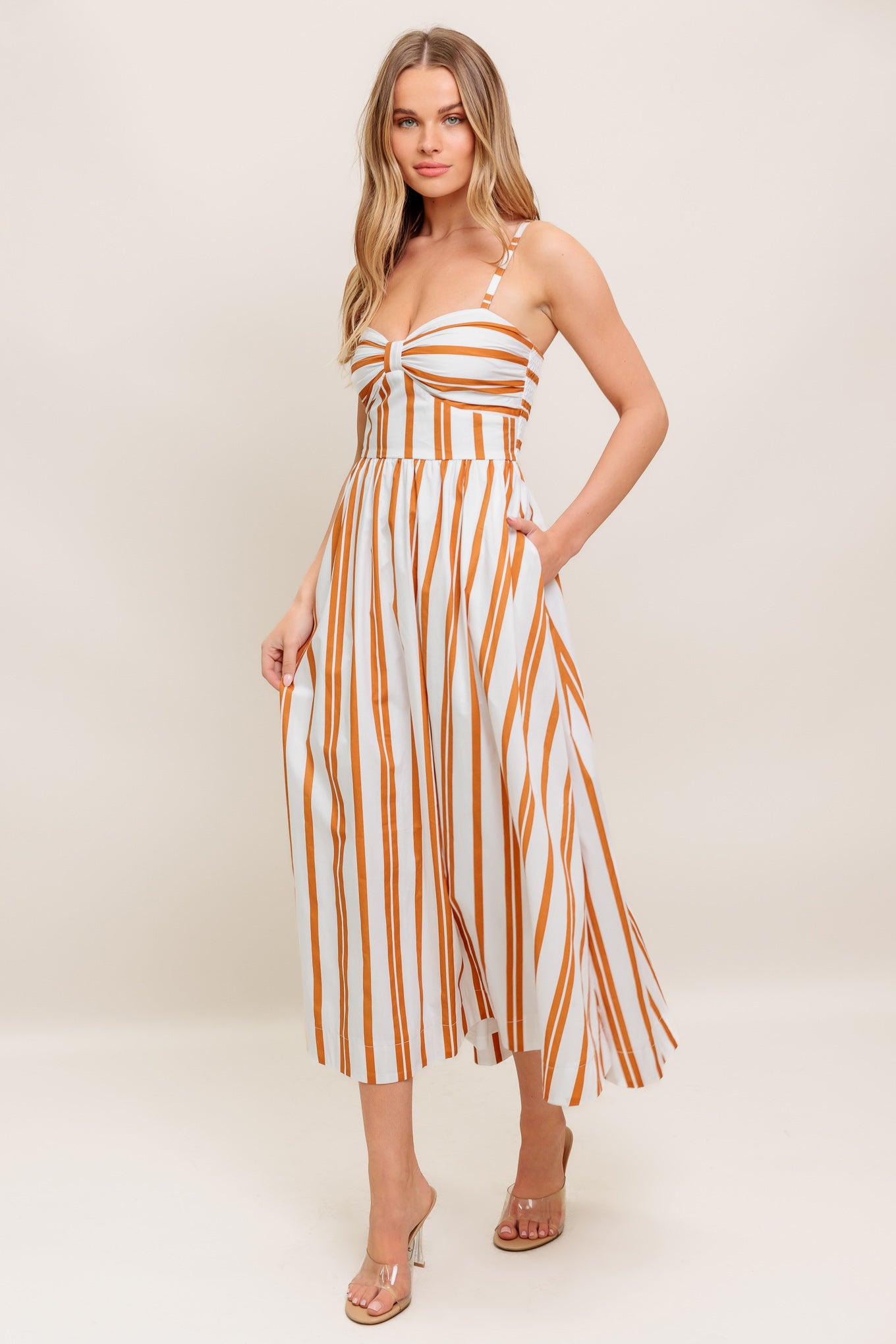 A striped woven midi dress featuring sweetheart neckline with shirred cup, straps, full skirt and smocked back bodice