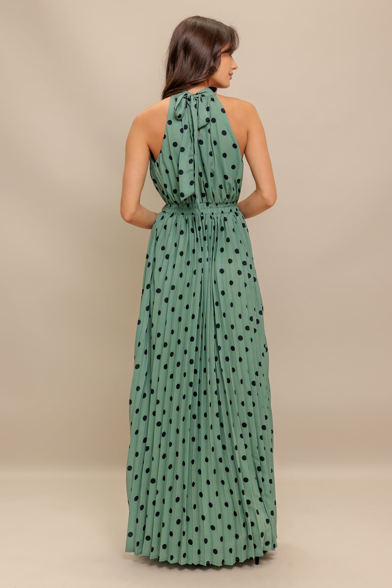 A printed woven maxi dress featuring halter neckline with back bow tie, sleeveless, pleated skirt and elasticized back waistband