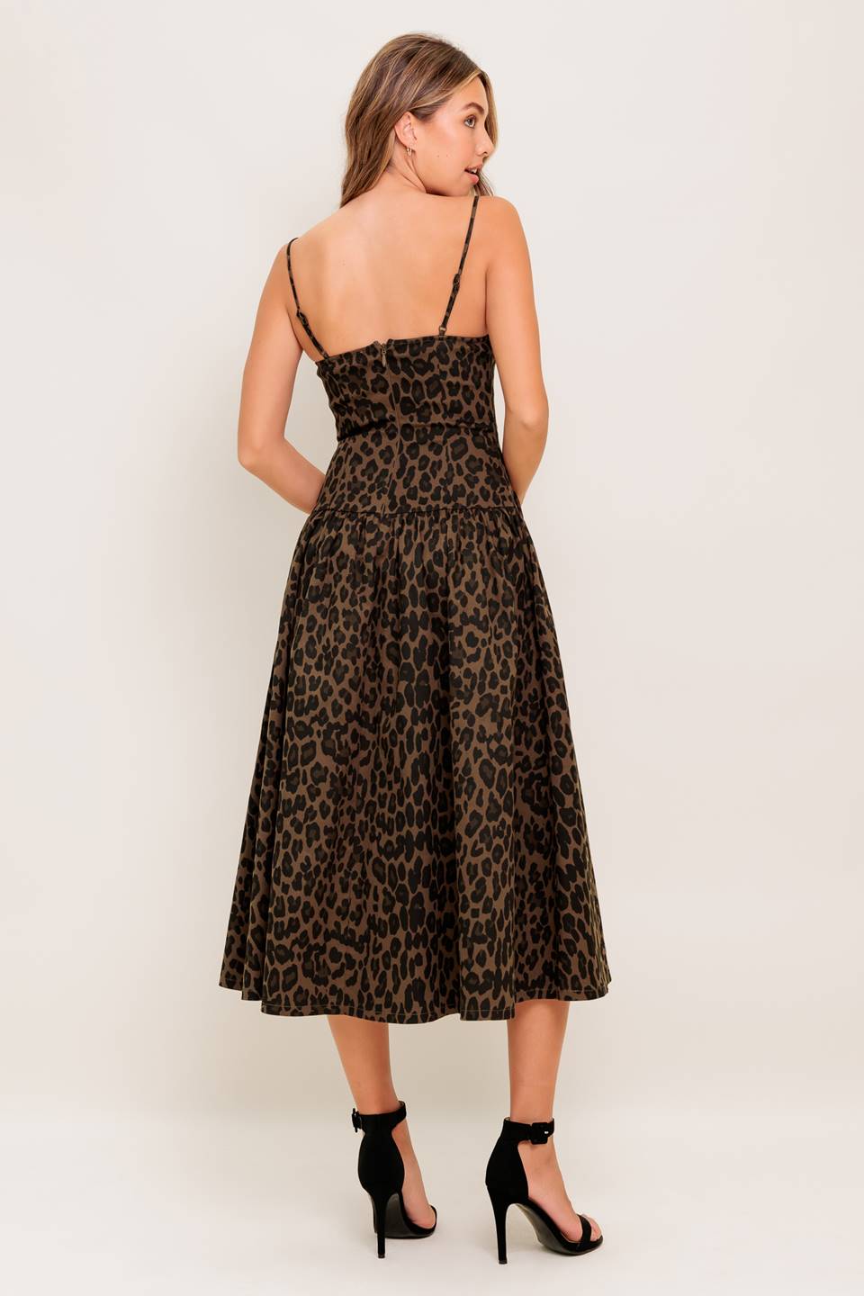 A leopard printed woven midi dress featuring straight neckline, strap, drop waist with bow detail, full skirt and back zipper closure