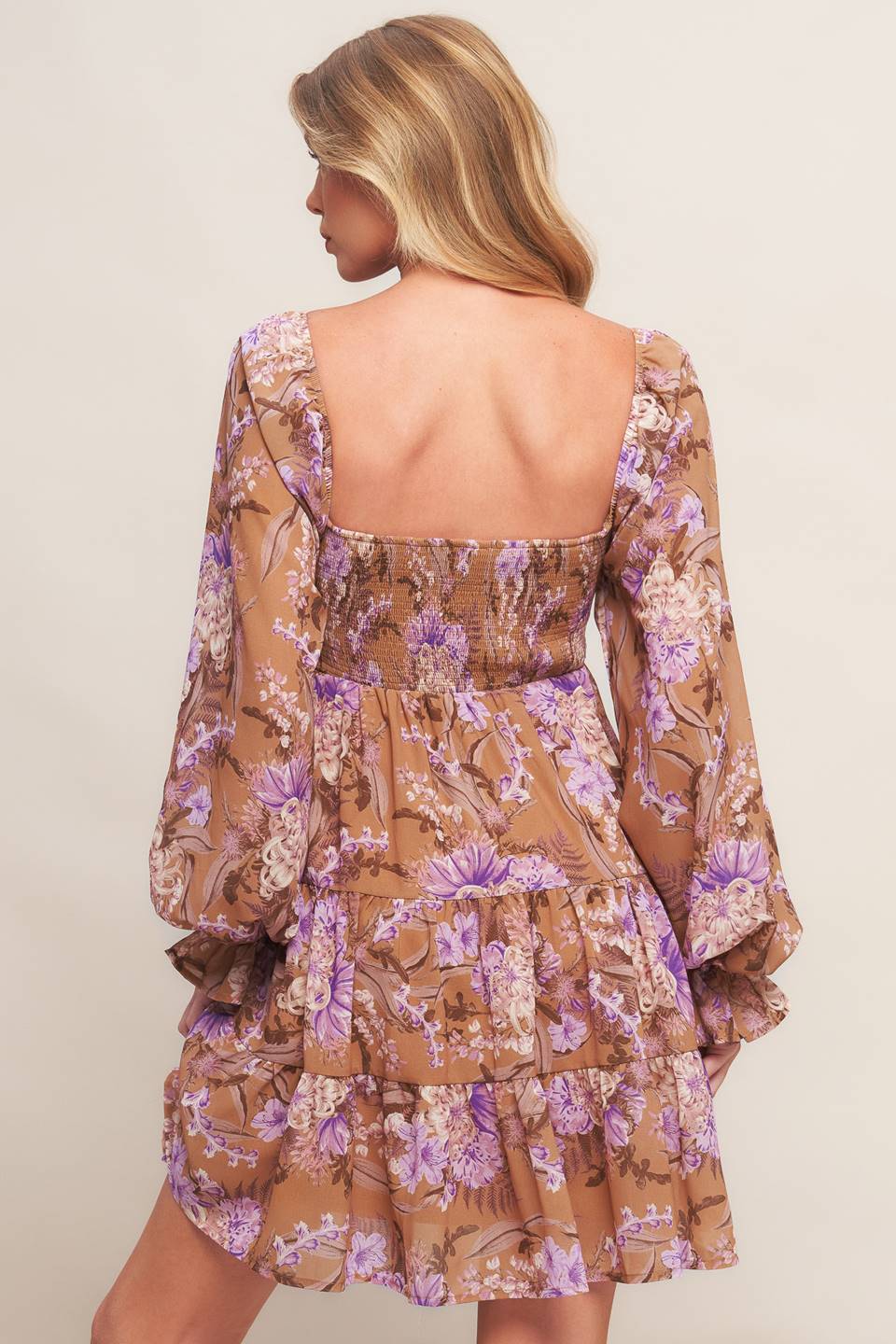 A printed woven mini dress featuring sweetheart neckline, smocked bodice, long sleeve with ruffled cuff and tiered skirt