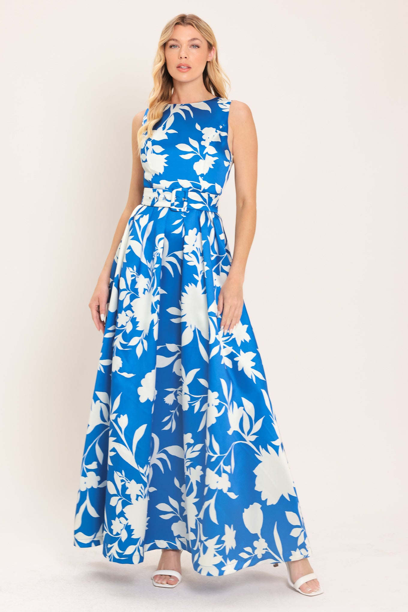 A woman wearing a sleeveless, blue maxi dress with a white floral print | Flying Tomato