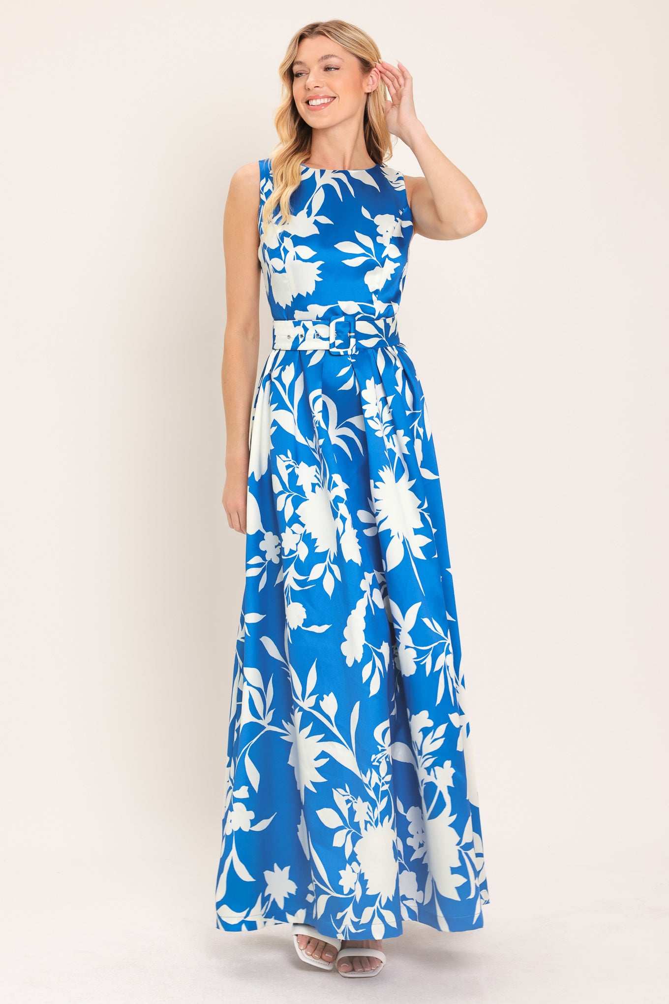 A woman wearing a sleeveless, blue maxi dress with a white floral print | Flying Tomato