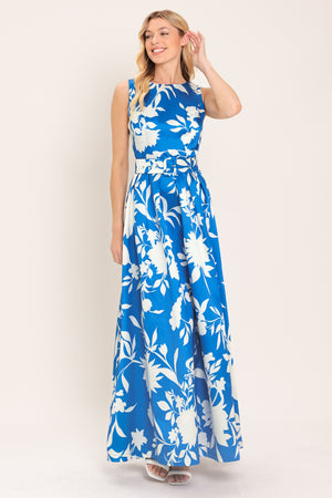 A woman wearing a sleeveless, blue maxi dress with a white floral print | Flying Tomato