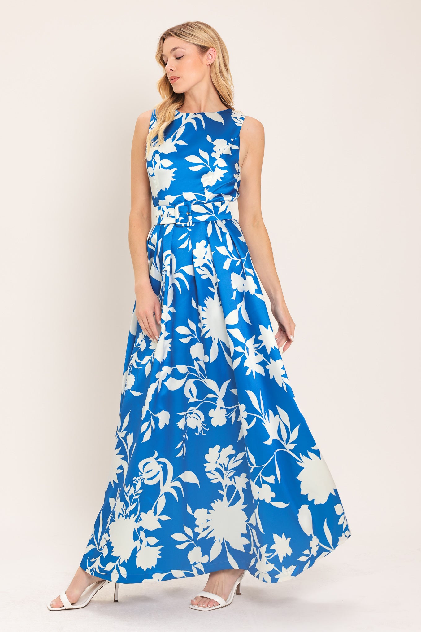 A woman wearing a sleeveless, blue maxi dress with a white floral print | Flying Tomato