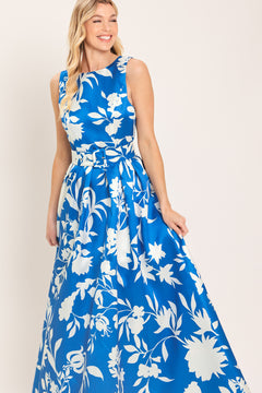 A woman wearing a sleeveless, blue maxi dress with a white floral print | Flying Tomato