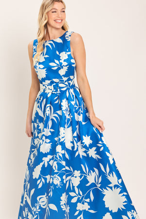 A woman wearing a sleeveless, blue maxi dress with a white floral print | Flying Tomato