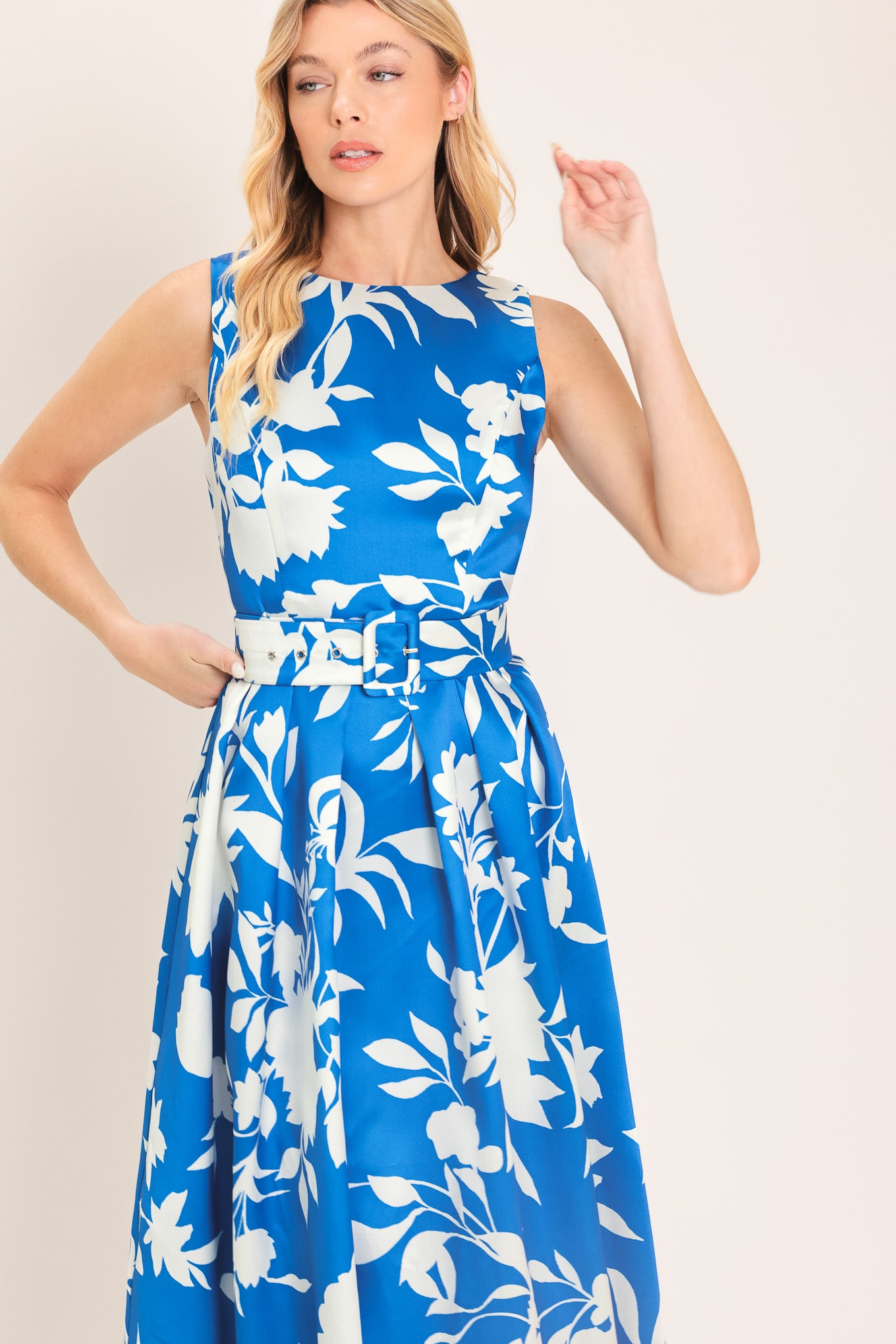 A woman wearing a sleeveless, blue maxi dress with a white floral print | Flying Tomato