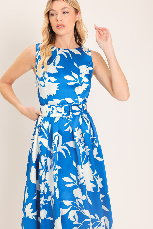 A woman wearing a sleeveless, blue maxi dress with a white floral print | Flying Tomato