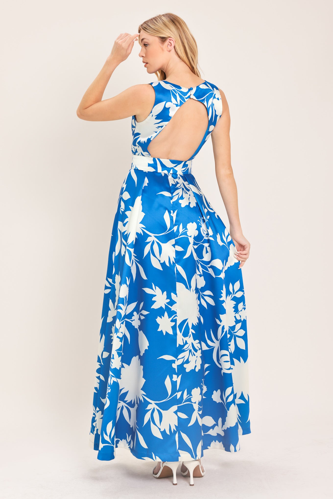 A woman wearing a sleeveless, blue maxi dress with a white floral print | Flying Tomato