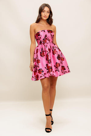 This strapless mini dress showcases a pink floral pattern on woven fabric, designed with a full skirt and secured by a back zipper closure.