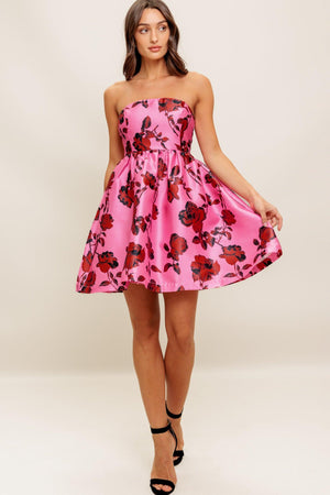 This strapless mini dress showcases a pink floral pattern on woven fabric, designed with a full skirt and secured by a back zipper closure.