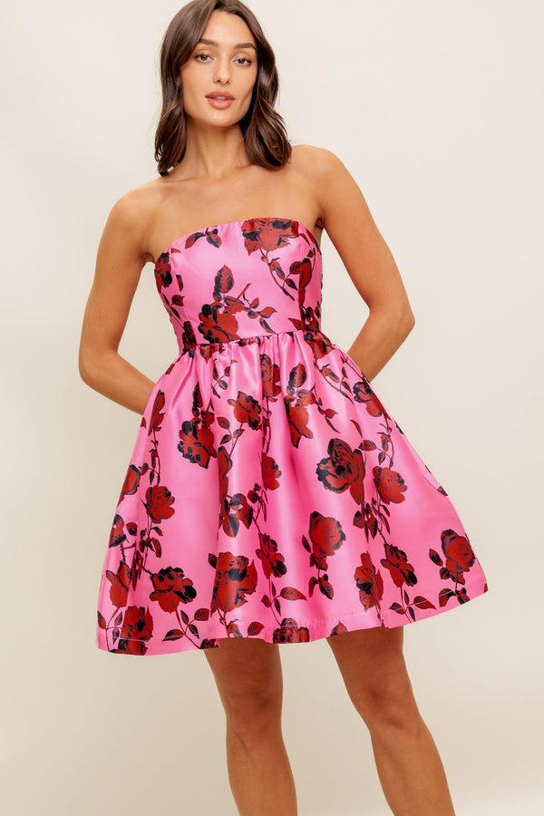 This strapless mini dress showcases a pink floral pattern on woven fabric, designed with a full skirt and secured by a back zipper closure.