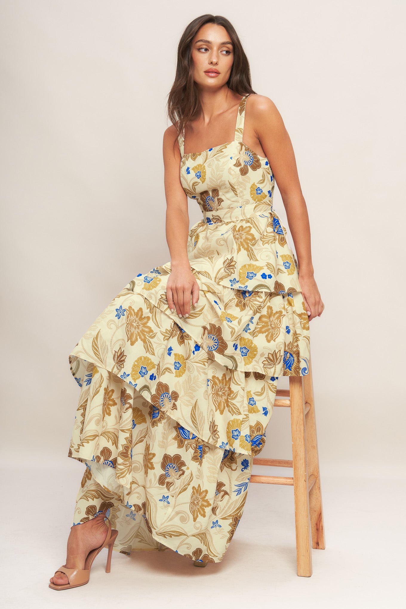 A printed woven maxi dress featuring straight neckline, straps, layered skirt and back zipper closure