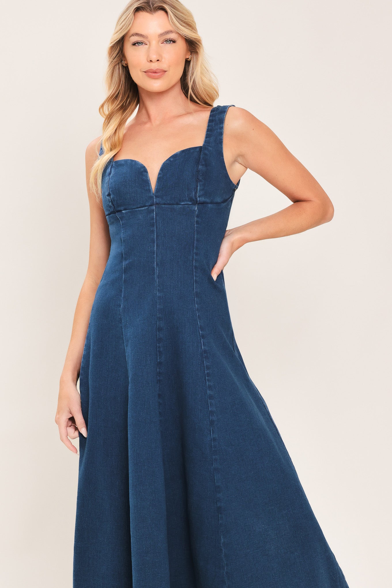 Woman wearing a sleeveless indigo denim midi dress featuring sweetheart neckline, circle skirt and back zipper closure | Flying Tomato