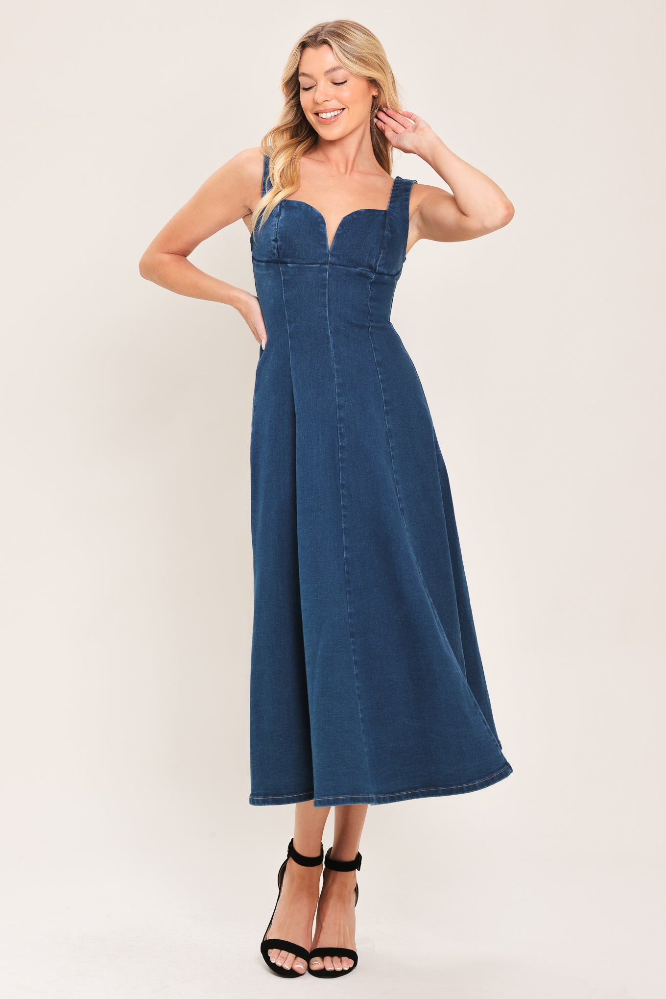 Woman wearing a sleeveless indigo denim midi dress featuring sweetheart neckline, circle skirt and back zipper closure | Flying Tomato