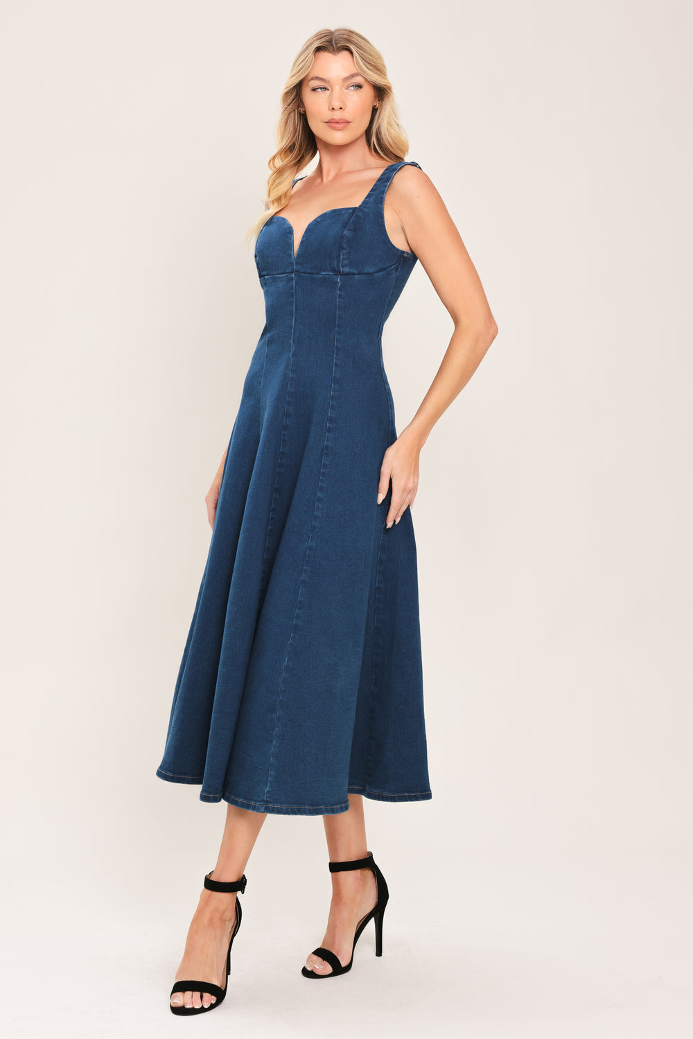 Woman wearing a sleeveless indigo denim midi dress featuring sweetheart neckline, circle skirt and back zipper closure | Flying Tomato
