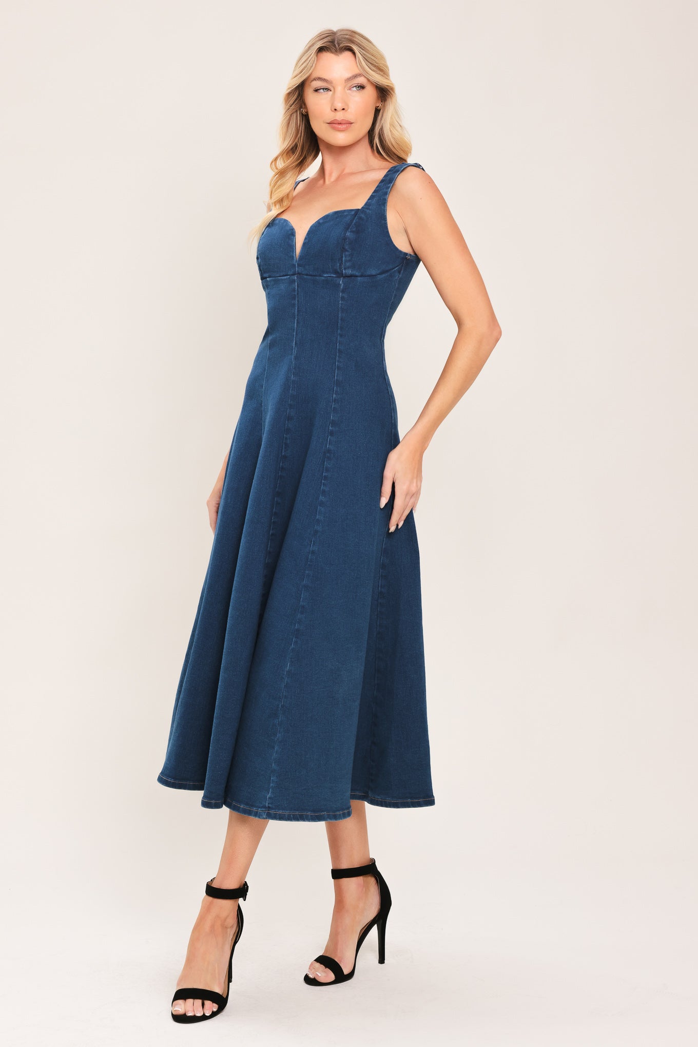 Woman wearing a sleeveless indigo denim midi dress featuring sweetheart neckline, circle skirt and back zipper closure | Flying Tomato