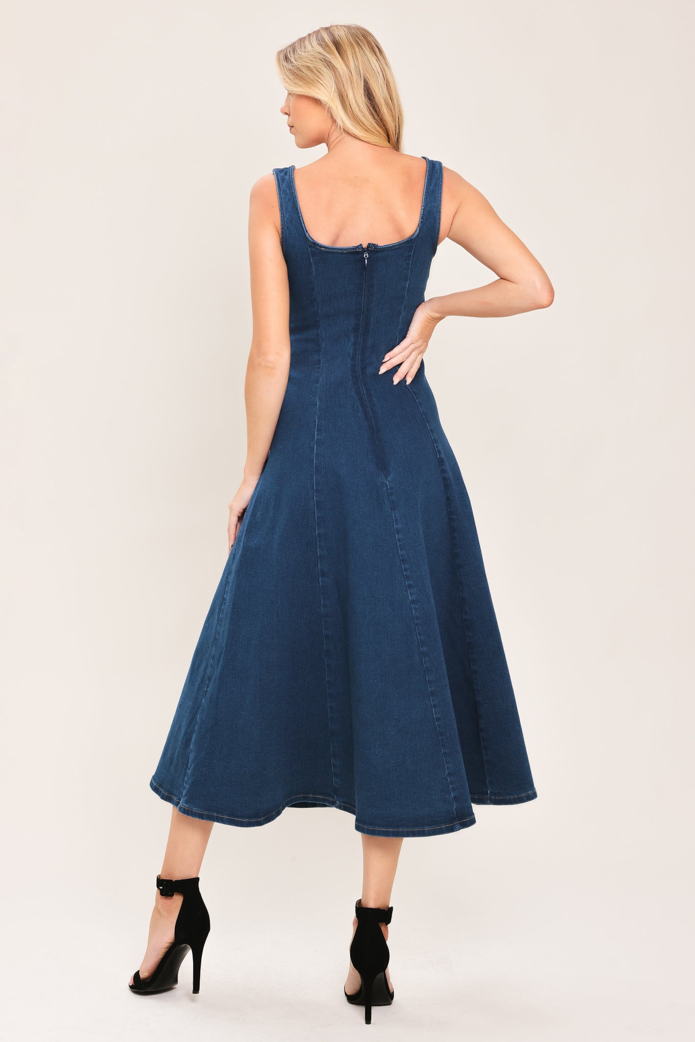 Woman wearing a sleeveless indigo denim midi dress featuring sweetheart neckline, circle skirt and back zipper closure | Flying Tomato