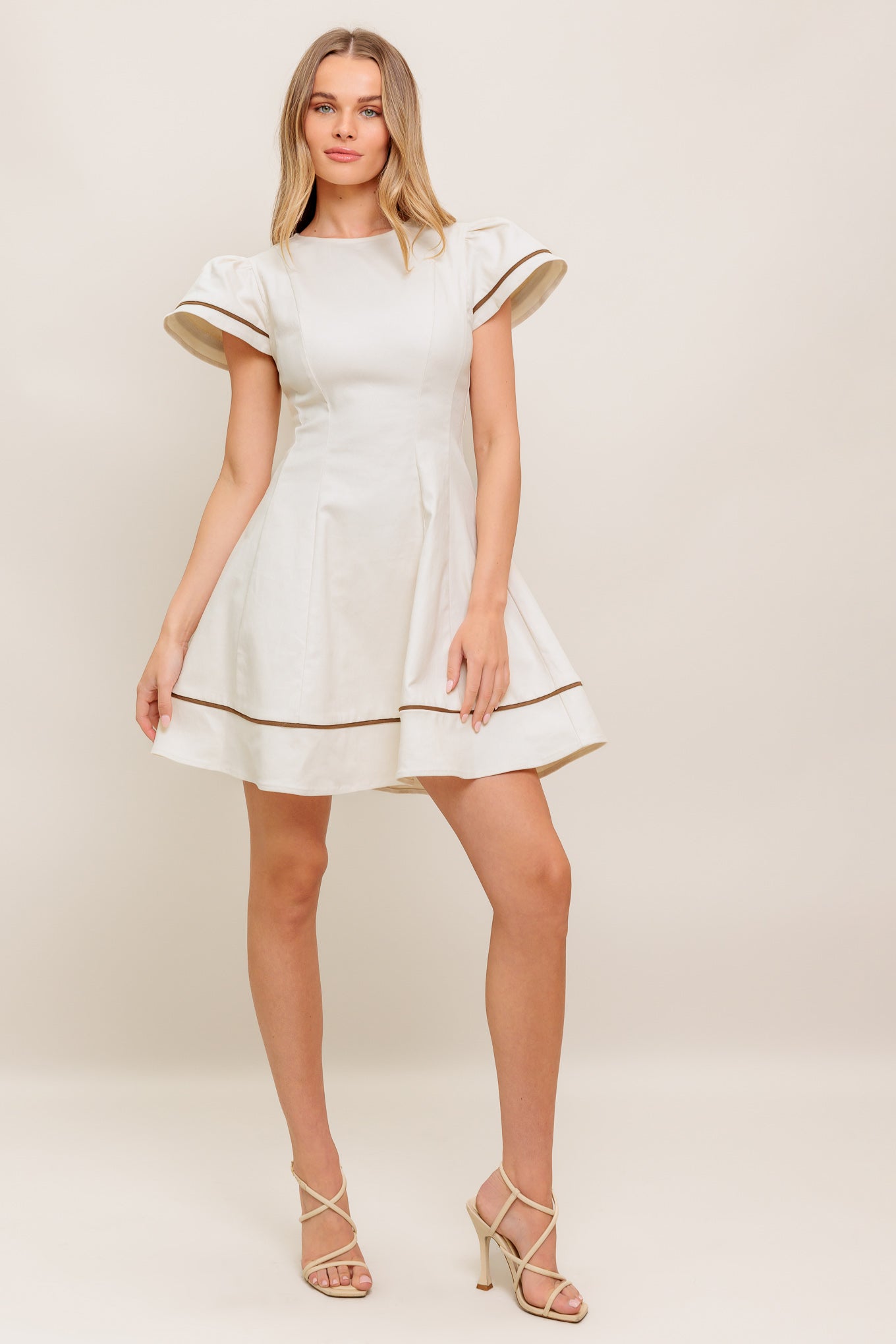 A solid woven mini dress featuring round neckline, short flutter sleeve, circle skirt and back zipper closure
