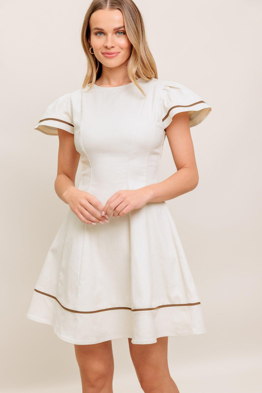 A solid woven mini dress featuring round neckline, short flutter sleeve, circle skirt and back zipper closure
