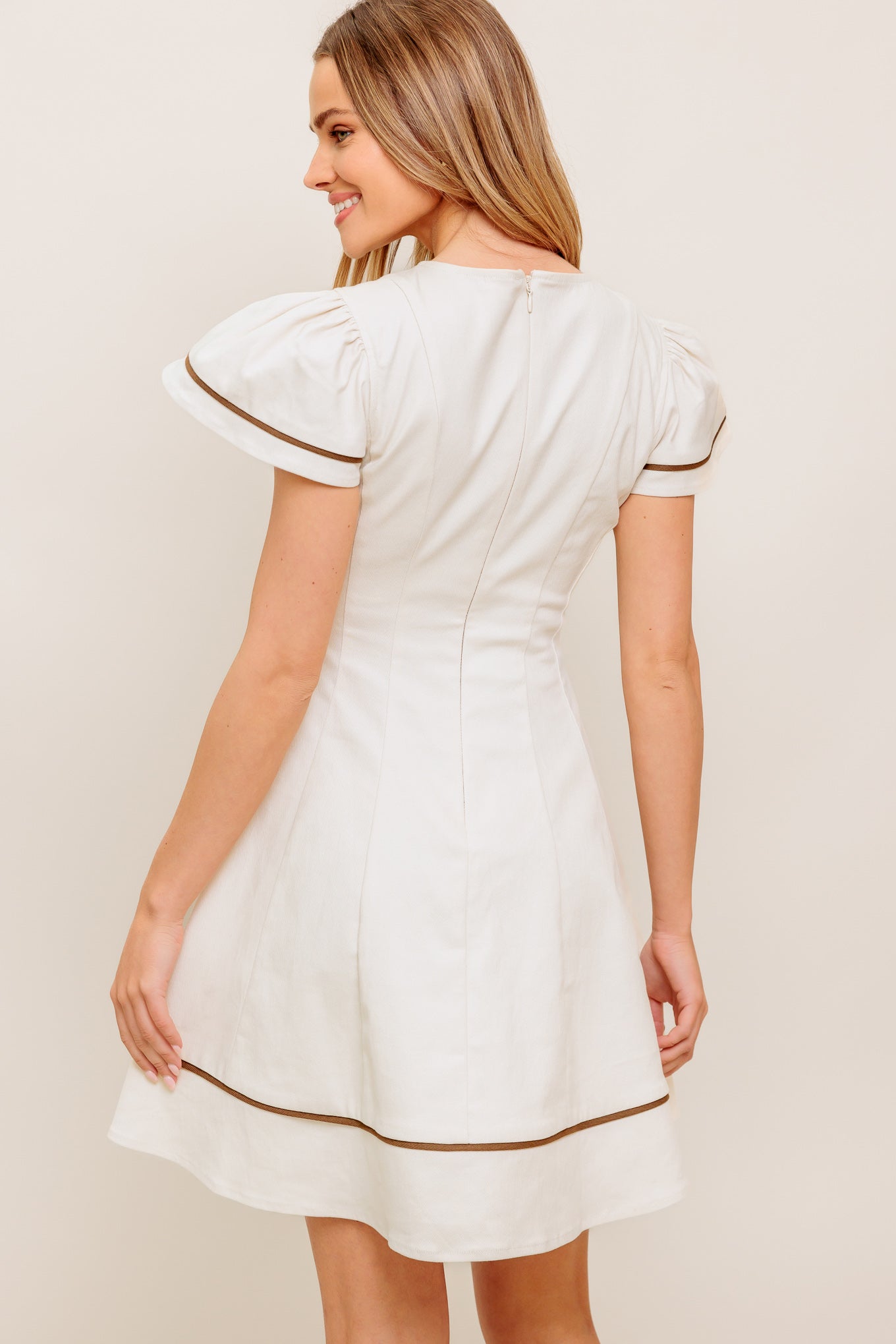 A solid woven mini dress featuring round neckline, short flutter sleeve, circle skirt and back zipper closure

