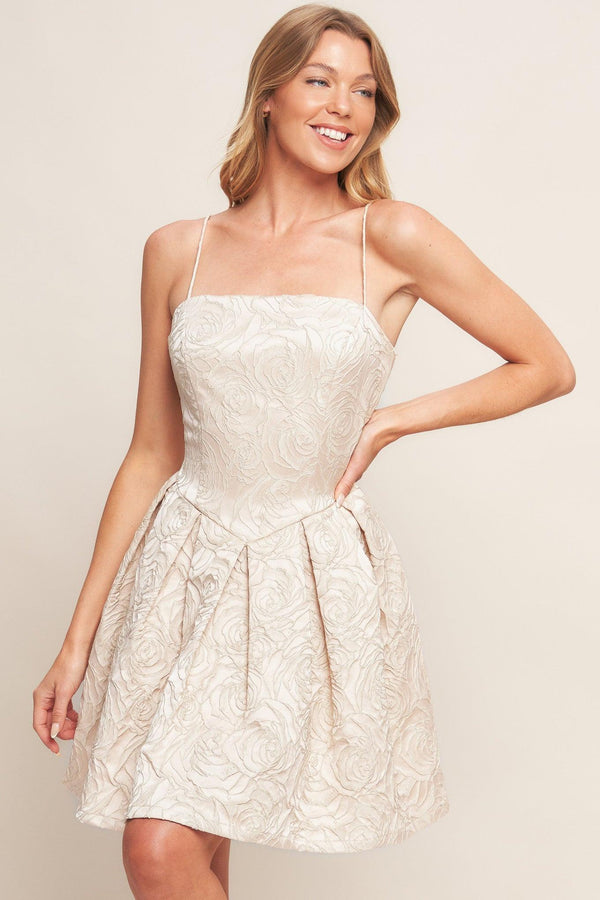 A textured woven mini dress featuring straight neckline, straps, basque waist, full skirt and back zipper closure