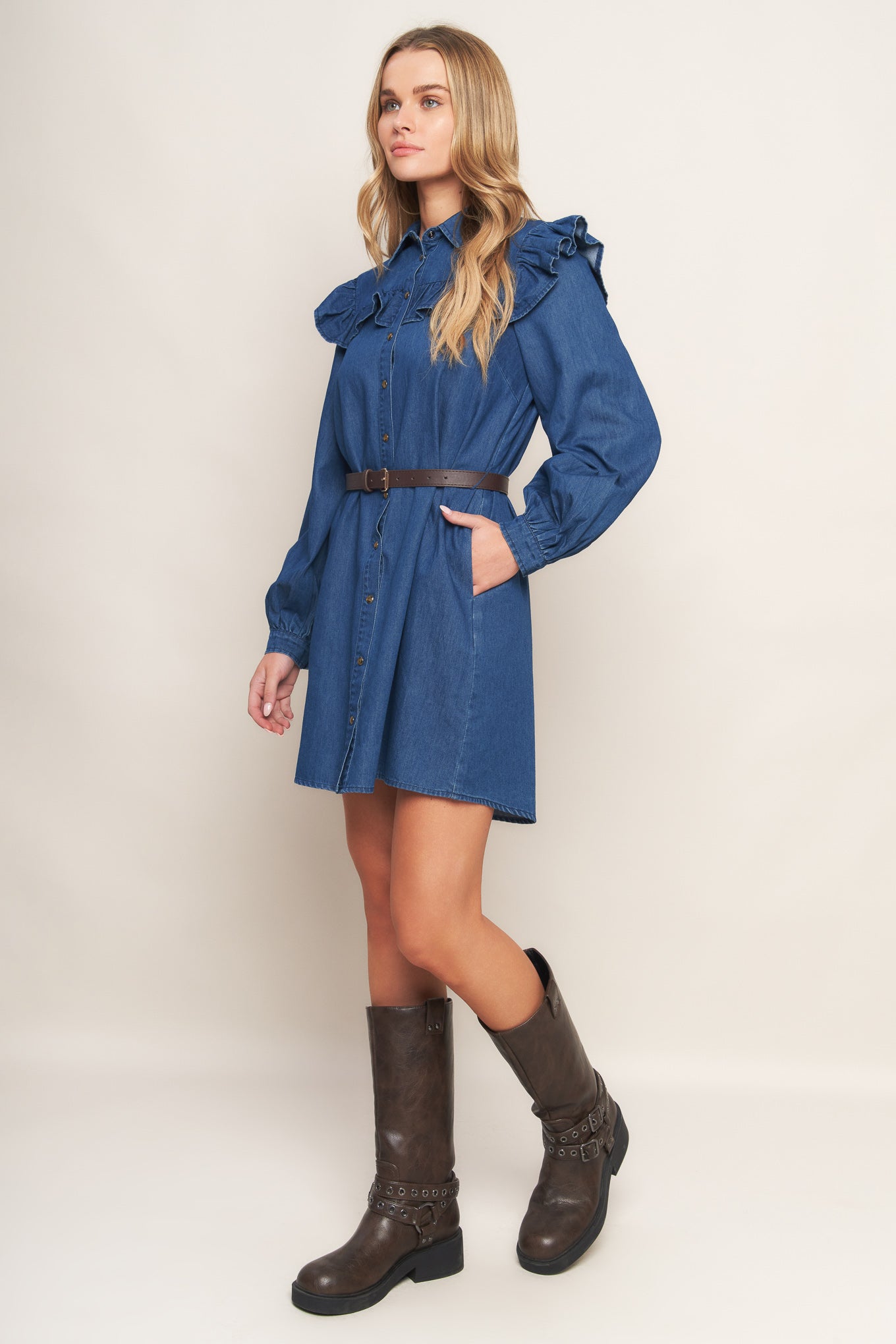 A denim mini dress featuring collar, square yoke with ruffles, long sleeve, front button down and contrasting belt