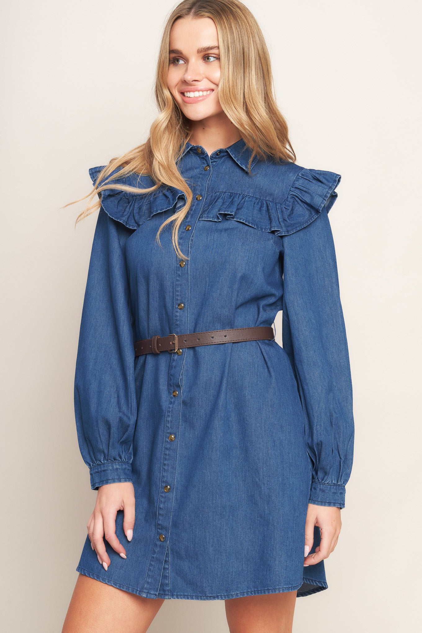 A denim mini dress featuring collar, square yoke with ruffles, long sleeve, front button down and contrasting belt