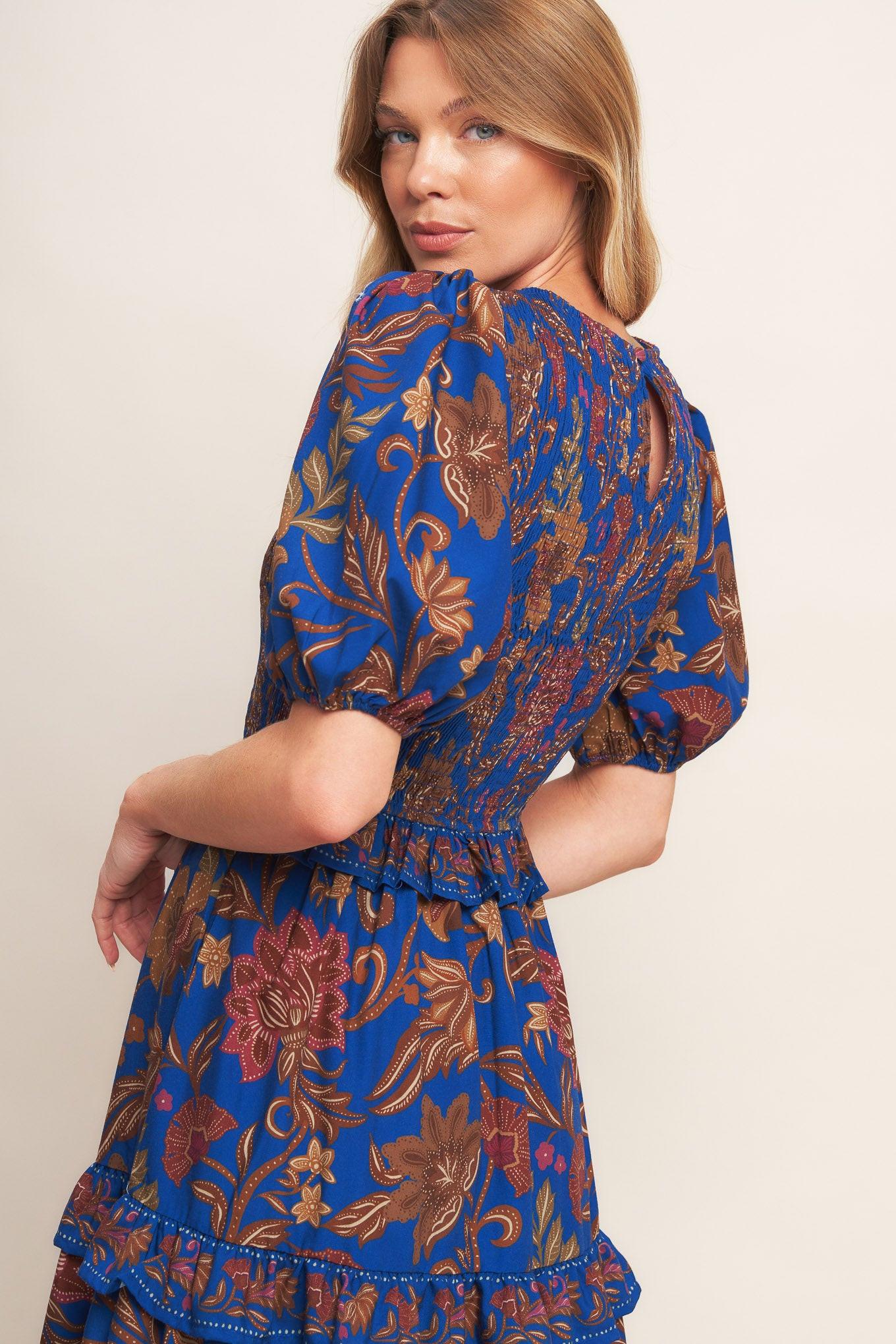 A printed woven midi dress featuring round neckline, smocked bodice, short puff sleeve, tiered skirt with ruffles and back neck button closure