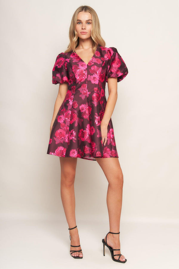 A printed woven mini dress featuring V neckline, short puff sleeve, circle skirt and back zipper closure