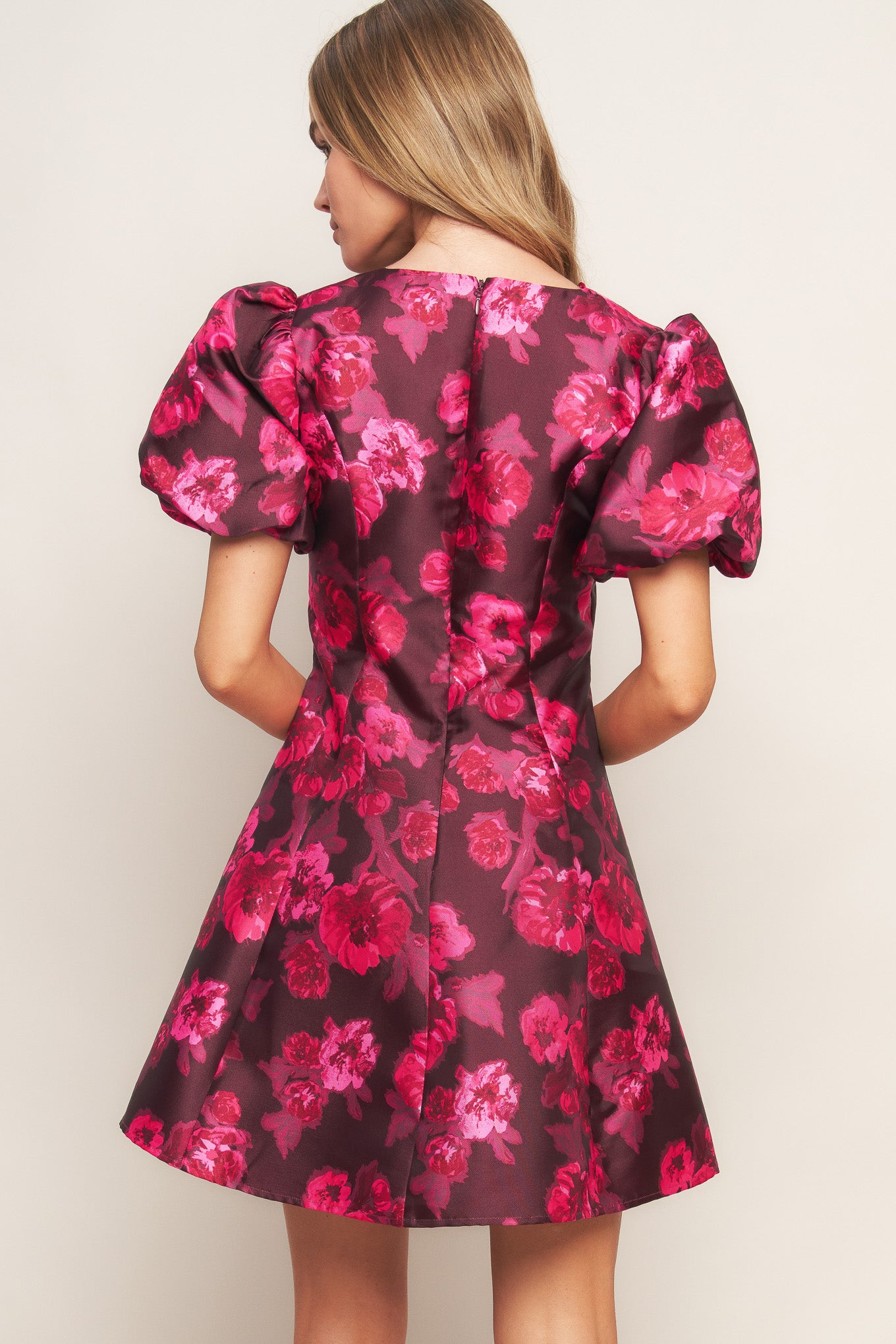 A printed woven mini dress featuring V neckline, short puff sleeve, circle skirt and back zipper closure