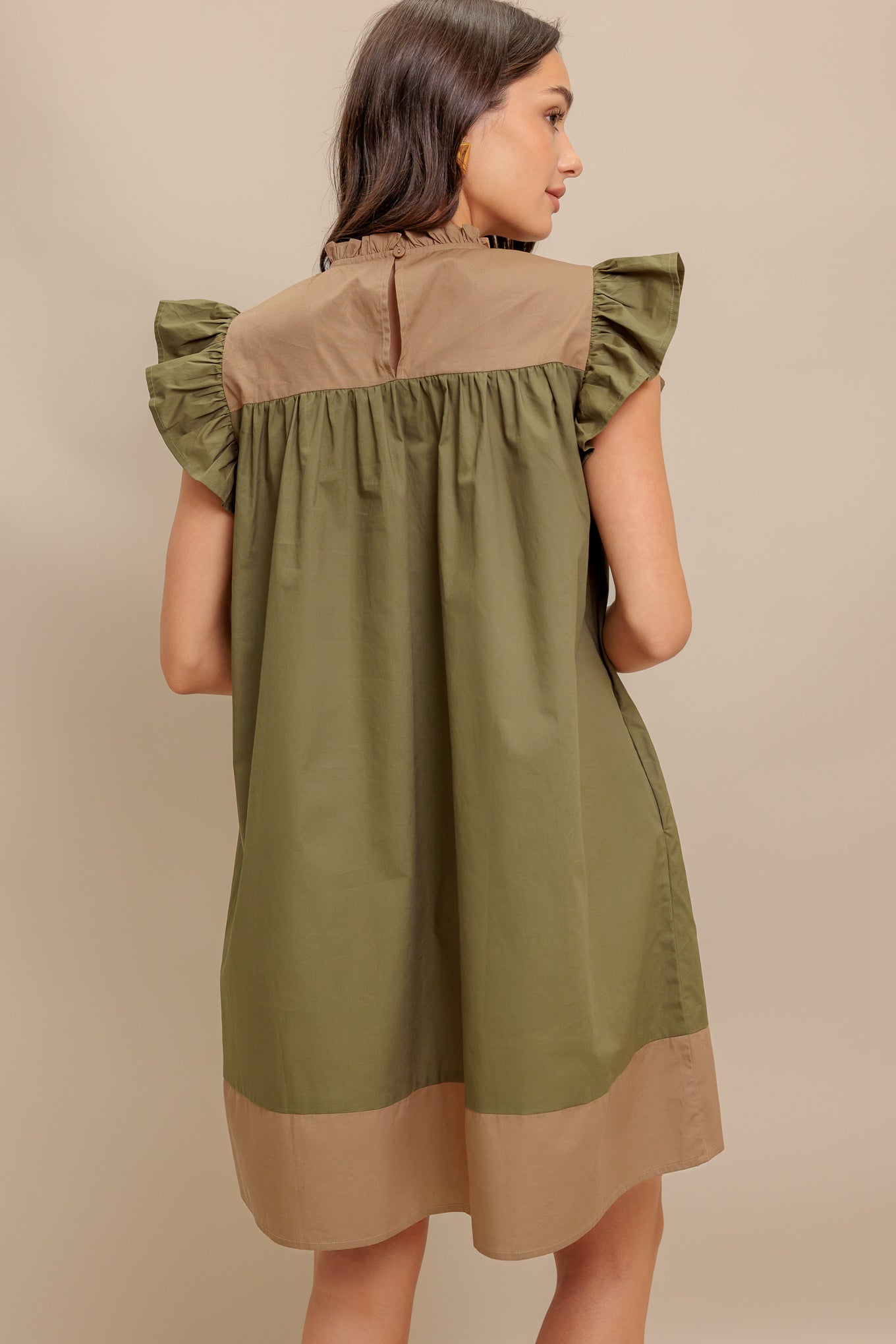 A color blocked woven mini dress featuring ruffled high neckline, ruffled short sleeve, pleated yoke and back neck button closure