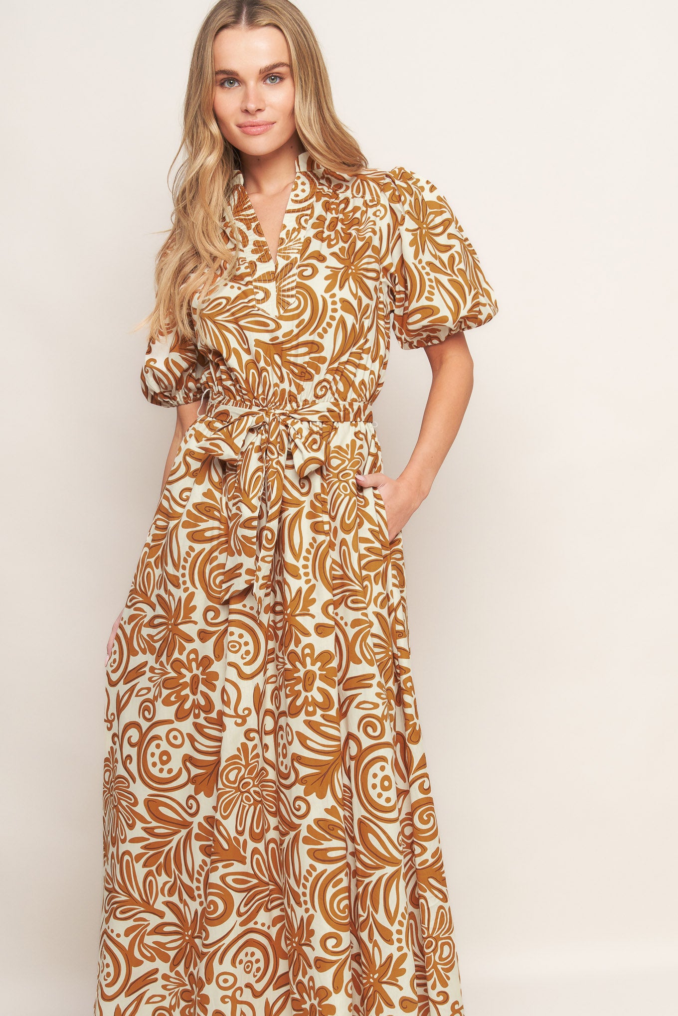 A printed woven midi dress featuring high neckline with center front V, short puff sleeve and elasticized waist with self sash tie