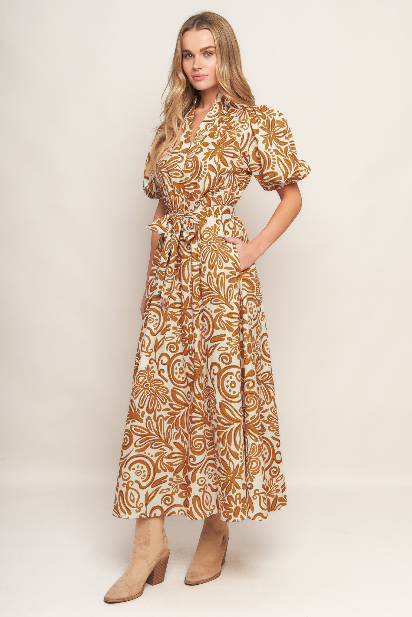 A printed woven midi dress featuring high neckline with center front V, short puff sleeve and elasticized waist with self sash tie