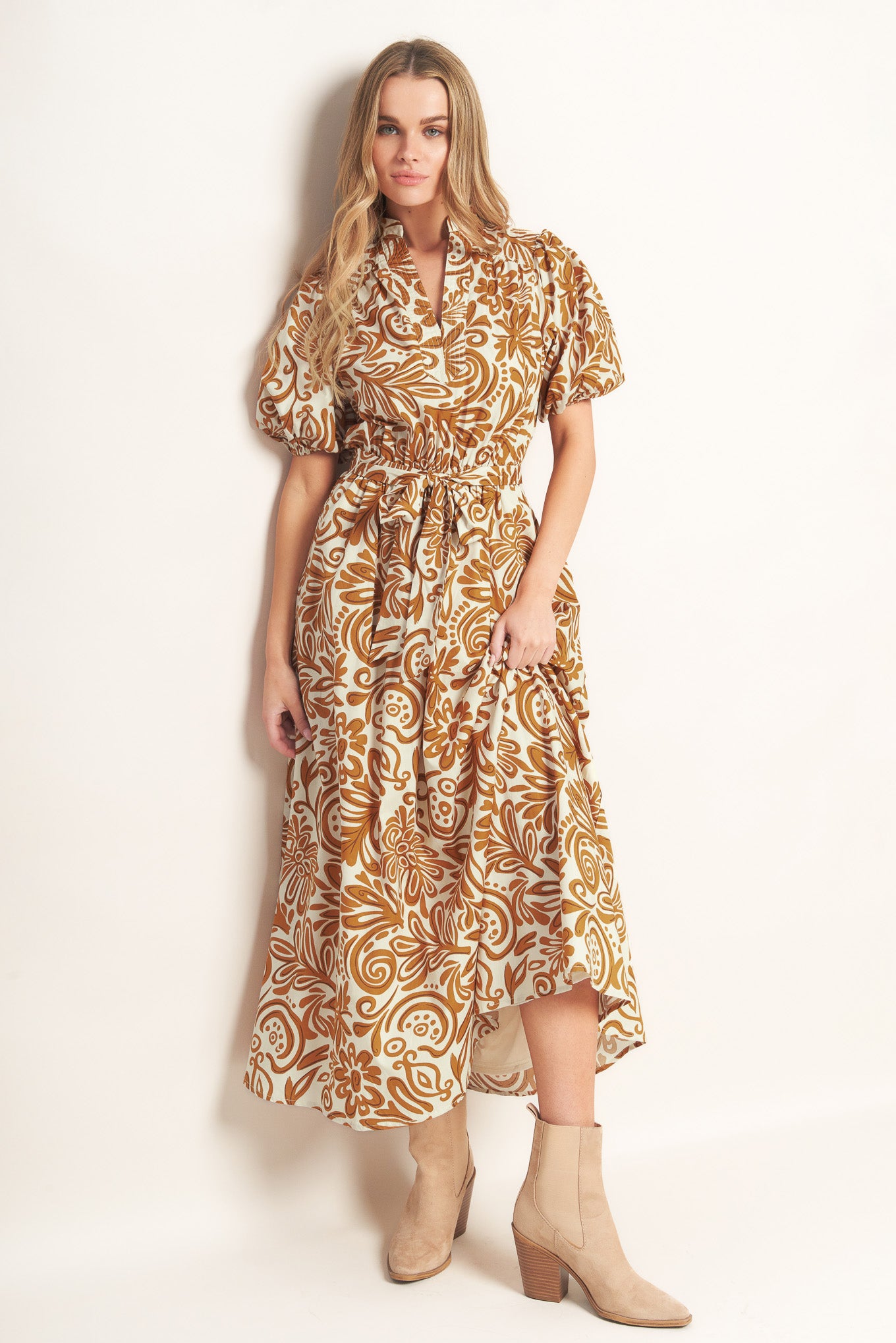 A printed woven midi dress featuring high neckline with center front V, short puff sleeve and elasticized waist with self sash tie