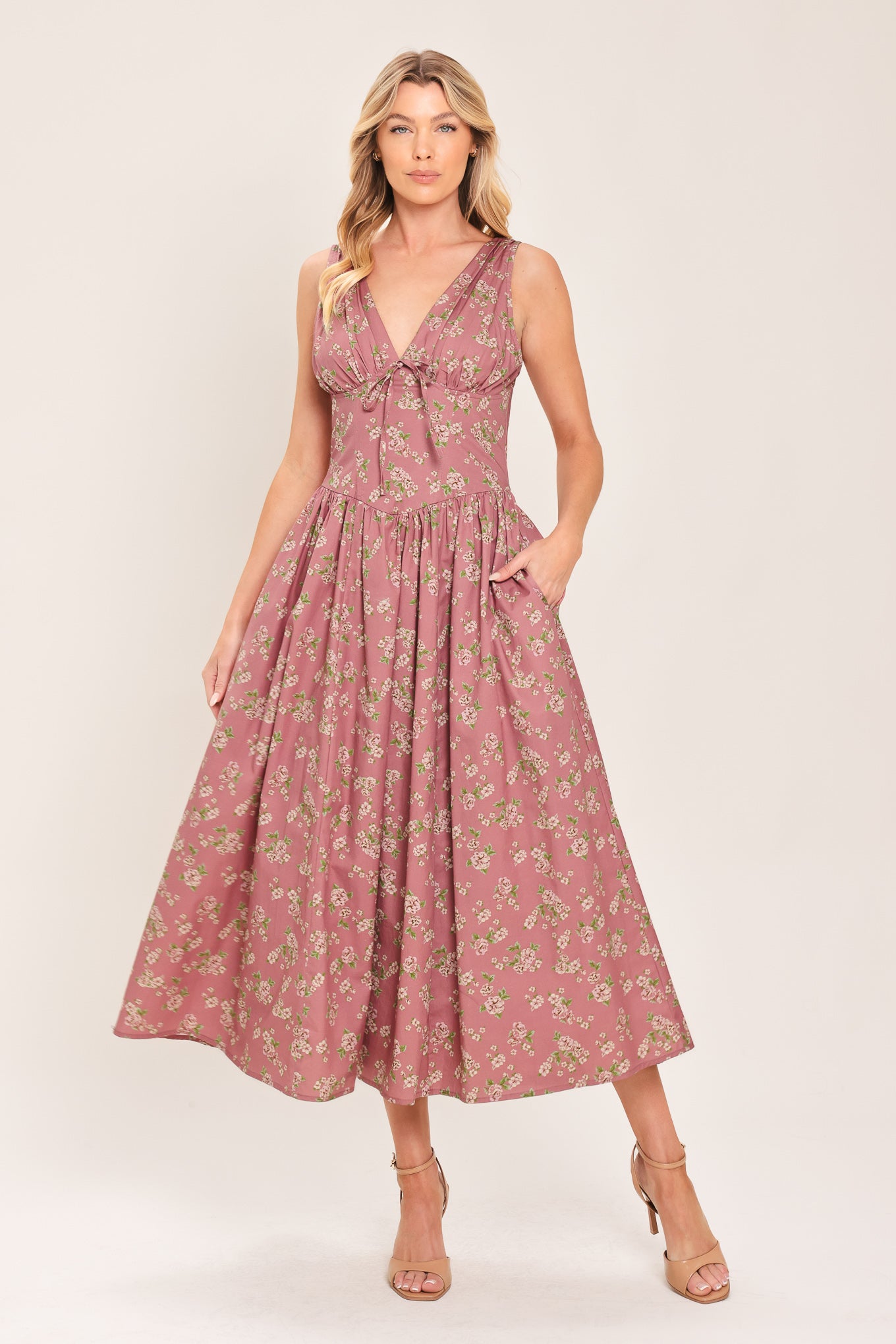 Woman wearing a mauve pink midi dress with small floral print and a woven featuring V neckline with bow tie, basque waistline, full skirt and back zipper closure | Flying Tomato