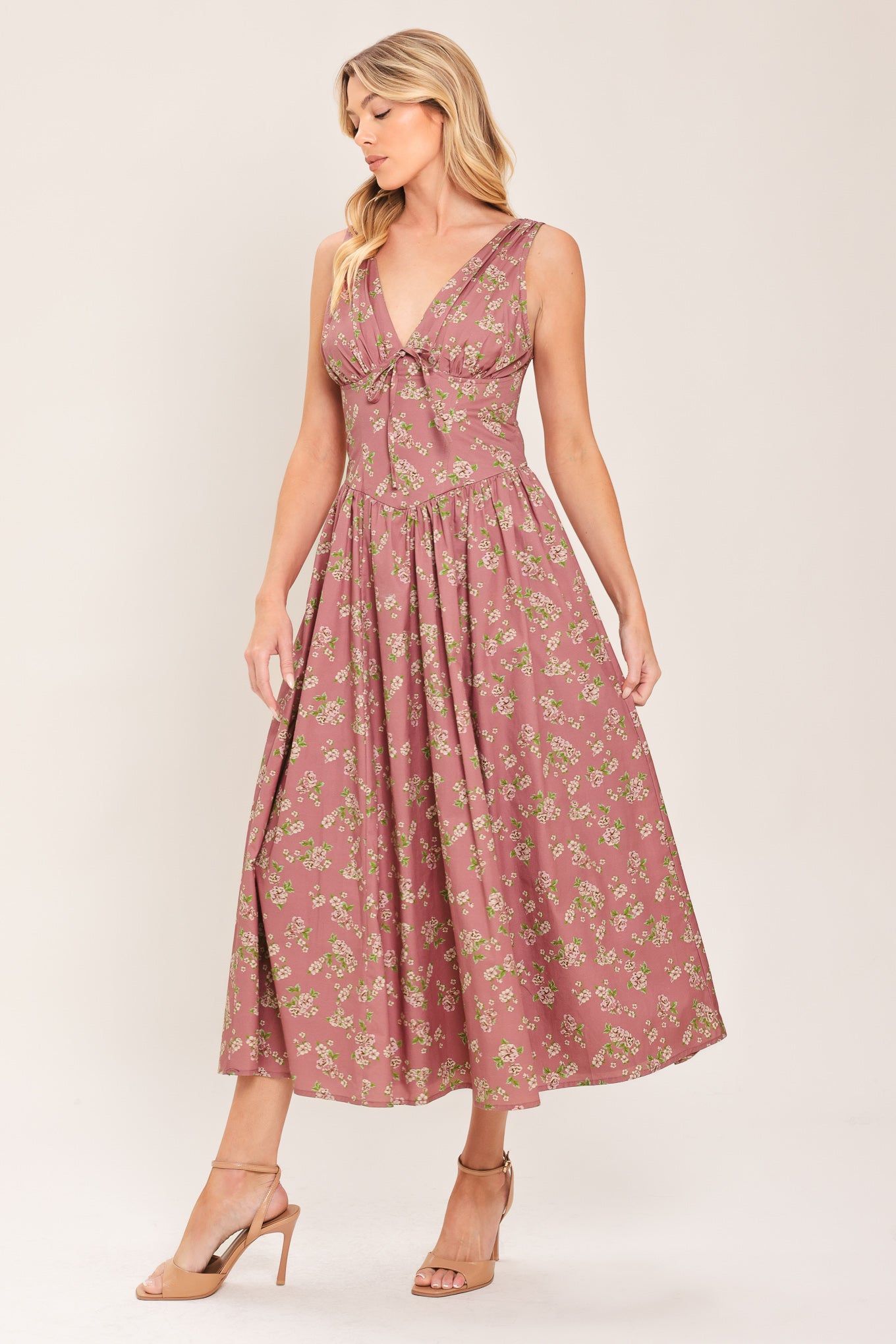 Woman wearing a mauve pink midi dress with small floral print and a woven featuring V neckline with bow tie, basque waistline, full skirt and back zipper closure | Flying Tomato