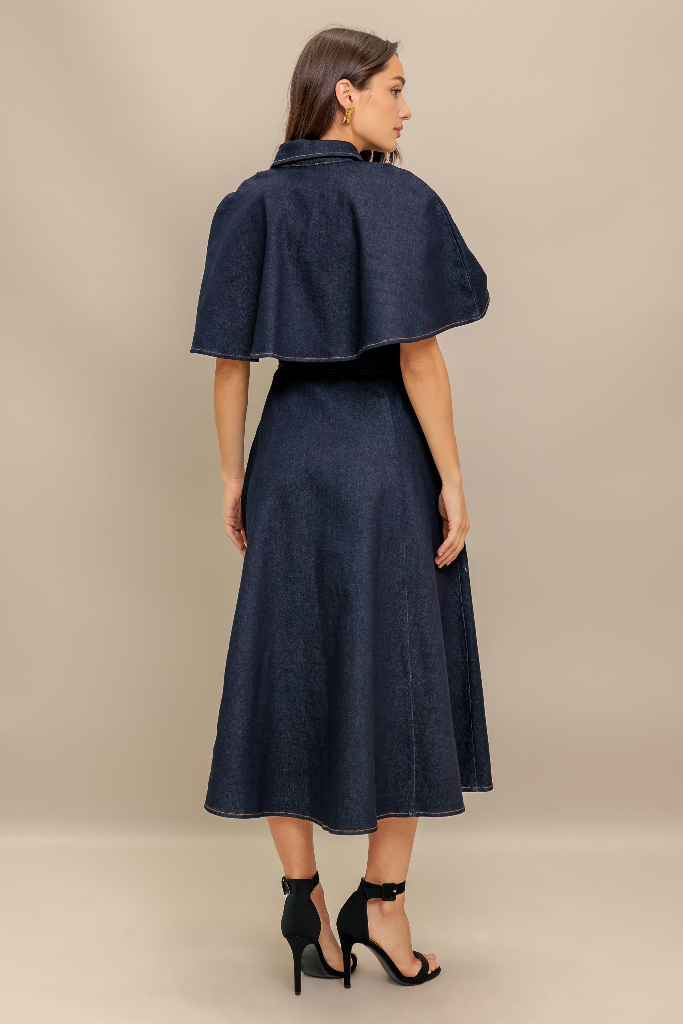 A denim midi dress featuring collar, front button down, cape top, self sash tie, and circle skirt