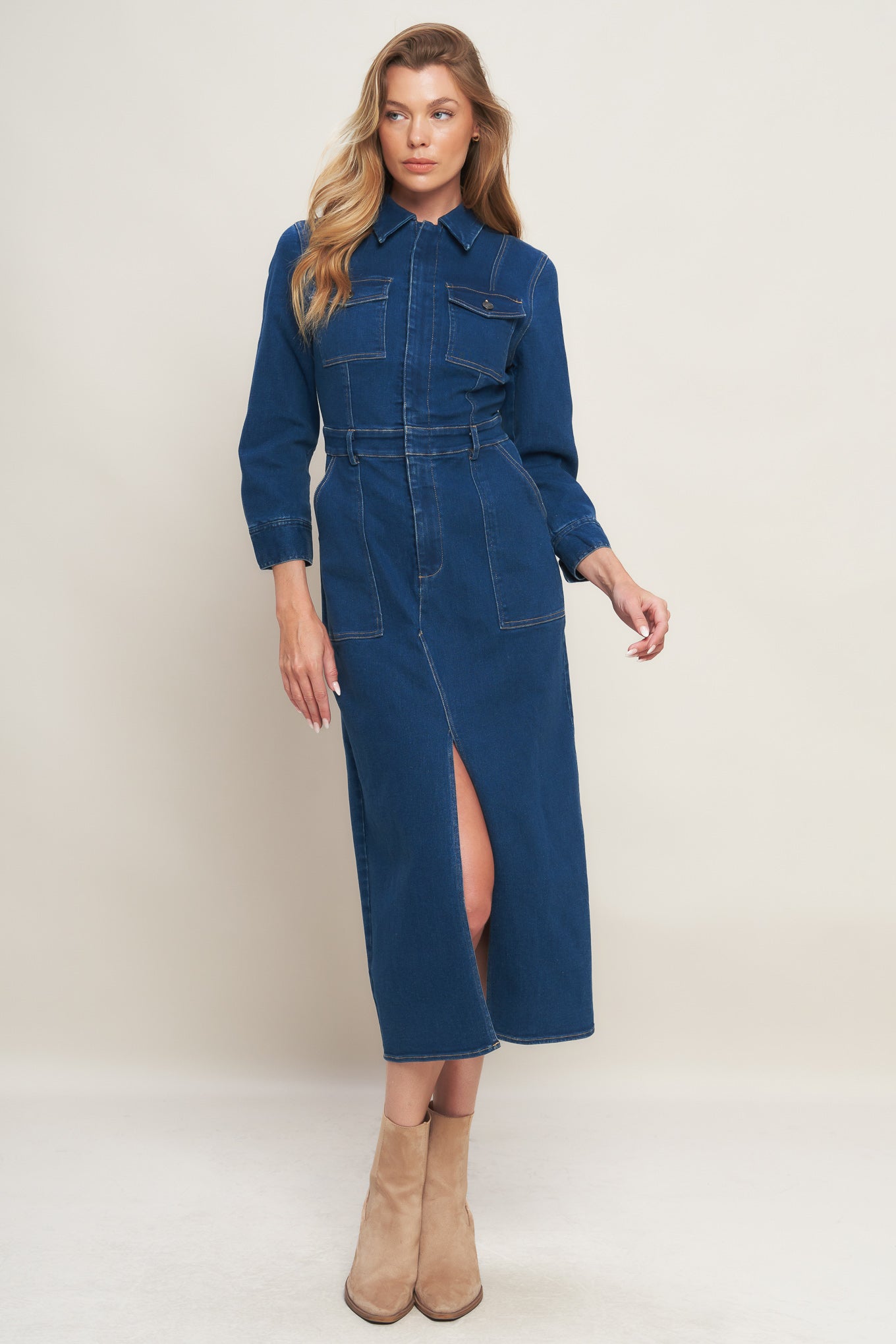 A washed denim midi dress featuring collar, hidden front zipper closure, long sleeve, front and side pockets with bottom front slit