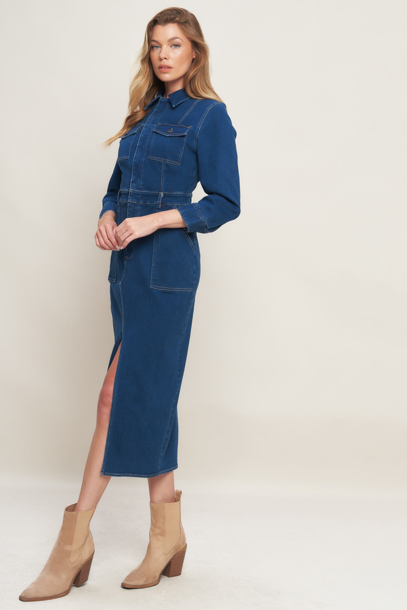 A washed denim midi dress featuring collar, hidden front zipper closure, long sleeve, front and side pockets with bottom front slit