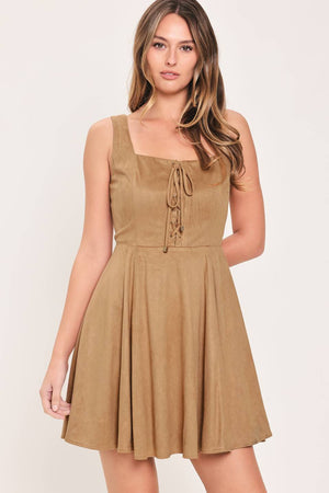 A woman modeling a sleeveless camel suede dress with a square neckline, front tie detail, and a flared skirt | Flying Tomato